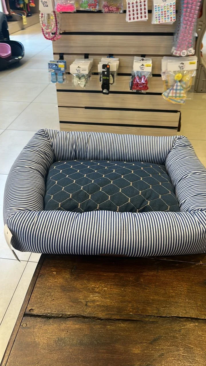 Foto real da manta azul sobre a almofada de uma cama pet listrada